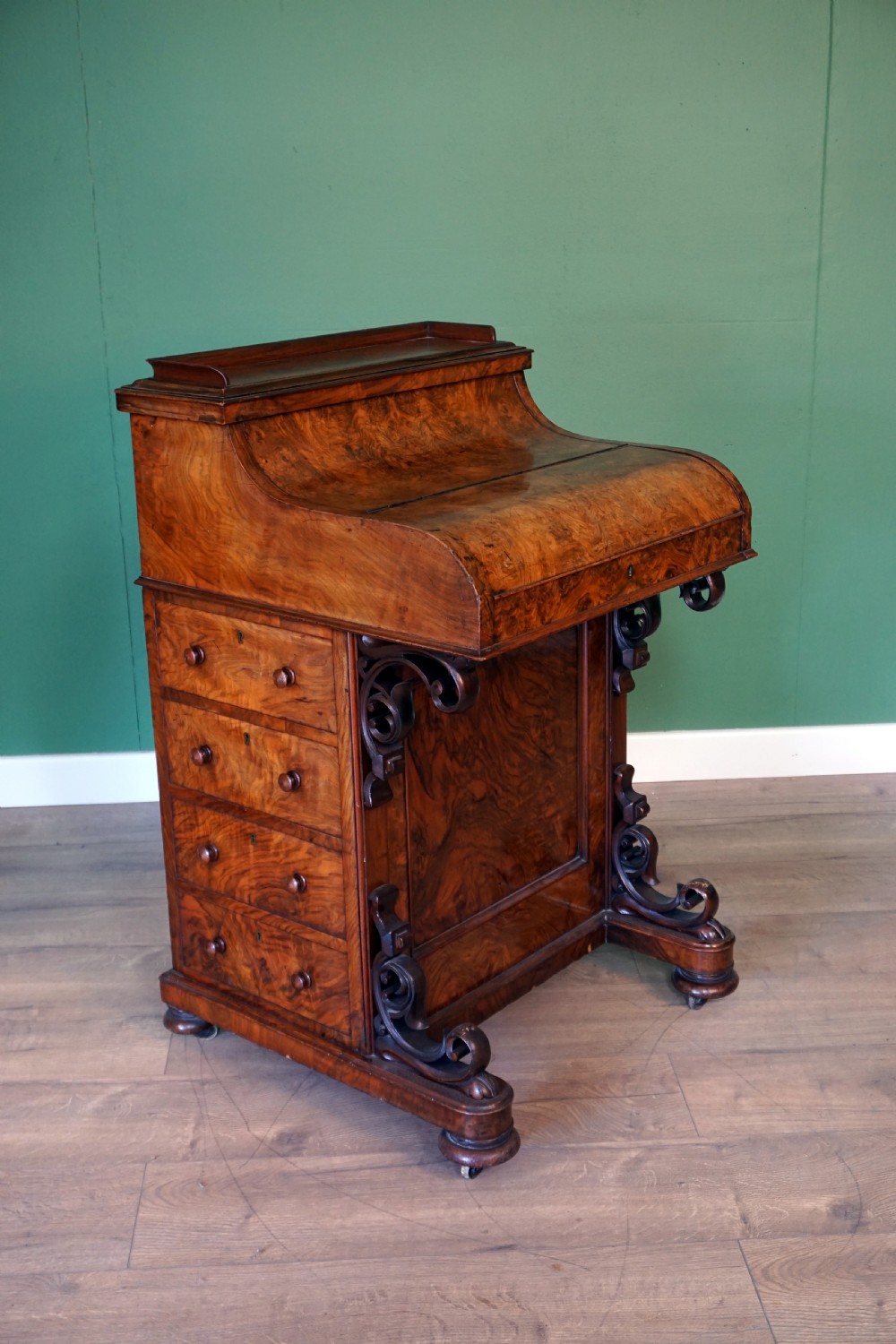 A Victorian burr walnut piano top davenport desk featuring scroll carved supports, side drawers, and a curved writing top section.