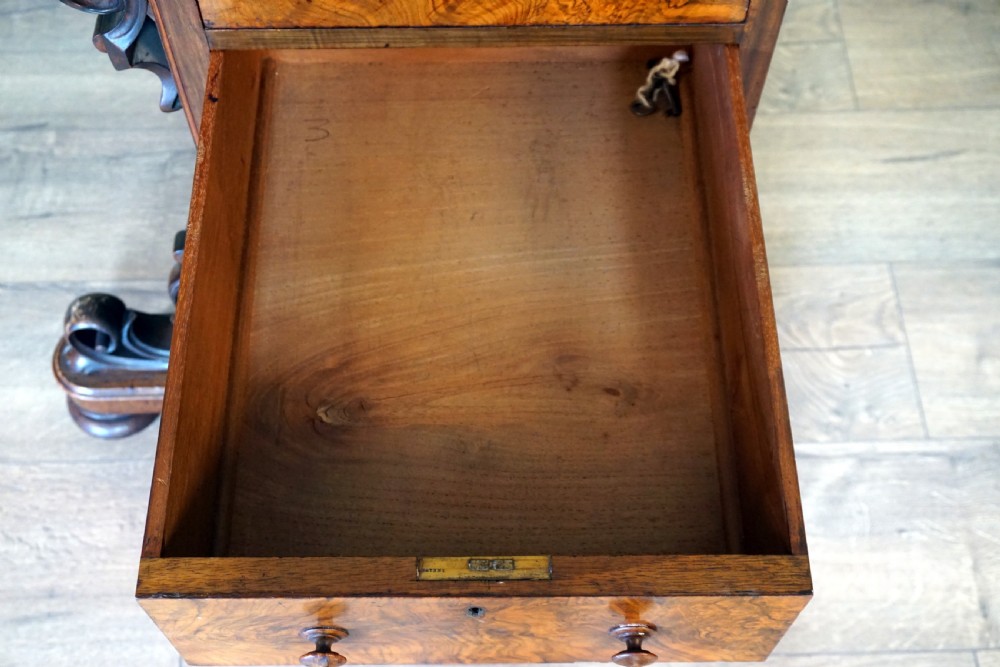 A Victorian burr walnut piano top davenport desk featuring scroll carved supports, side drawers, and a curved writing top section. View V