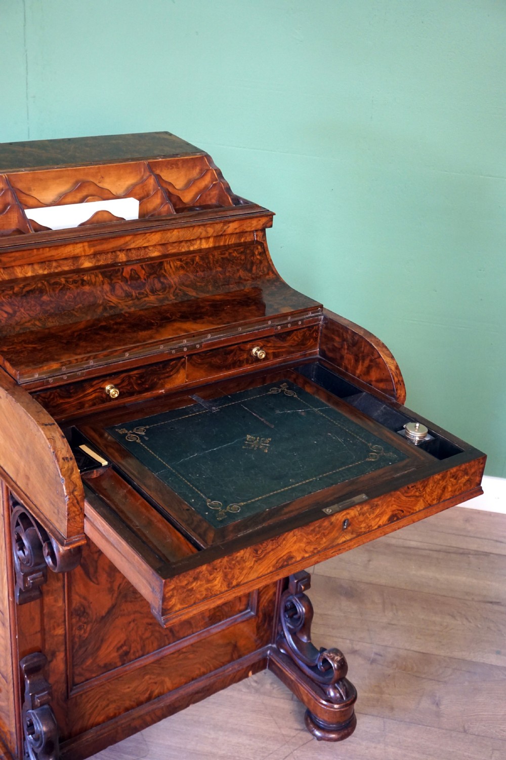 A Victorian burr walnut piano top davenport desk featuring scroll carved supports, side drawers, and a curved writing top section. View IX