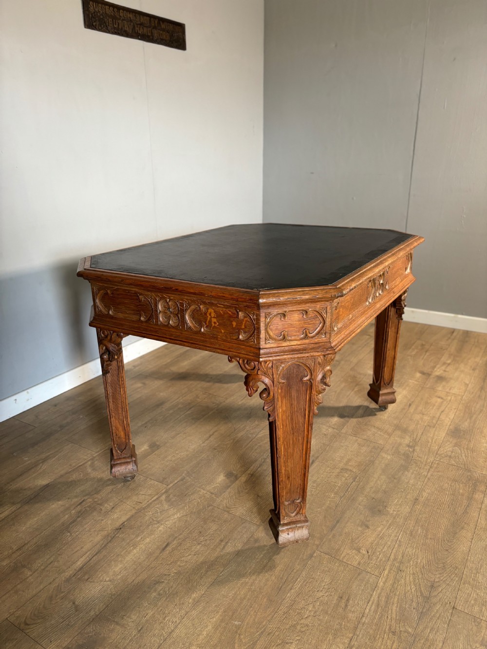 A Victorian Gothic Revival oak writing table featuring a dark leather inset top, carved quatrefoil frieze details, and detailed corner legs on castors. View III