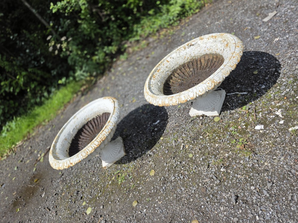 A pair of Victorian cast iron tazza garden urns with fluted basins and weathered white paint. View V