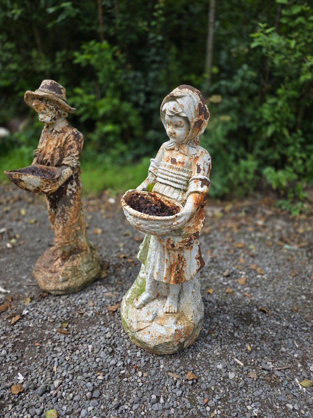 A pair of early 20th-century cast iron garden statues depicting a boy and girl in traditional attire holding small shallow basins. View VII