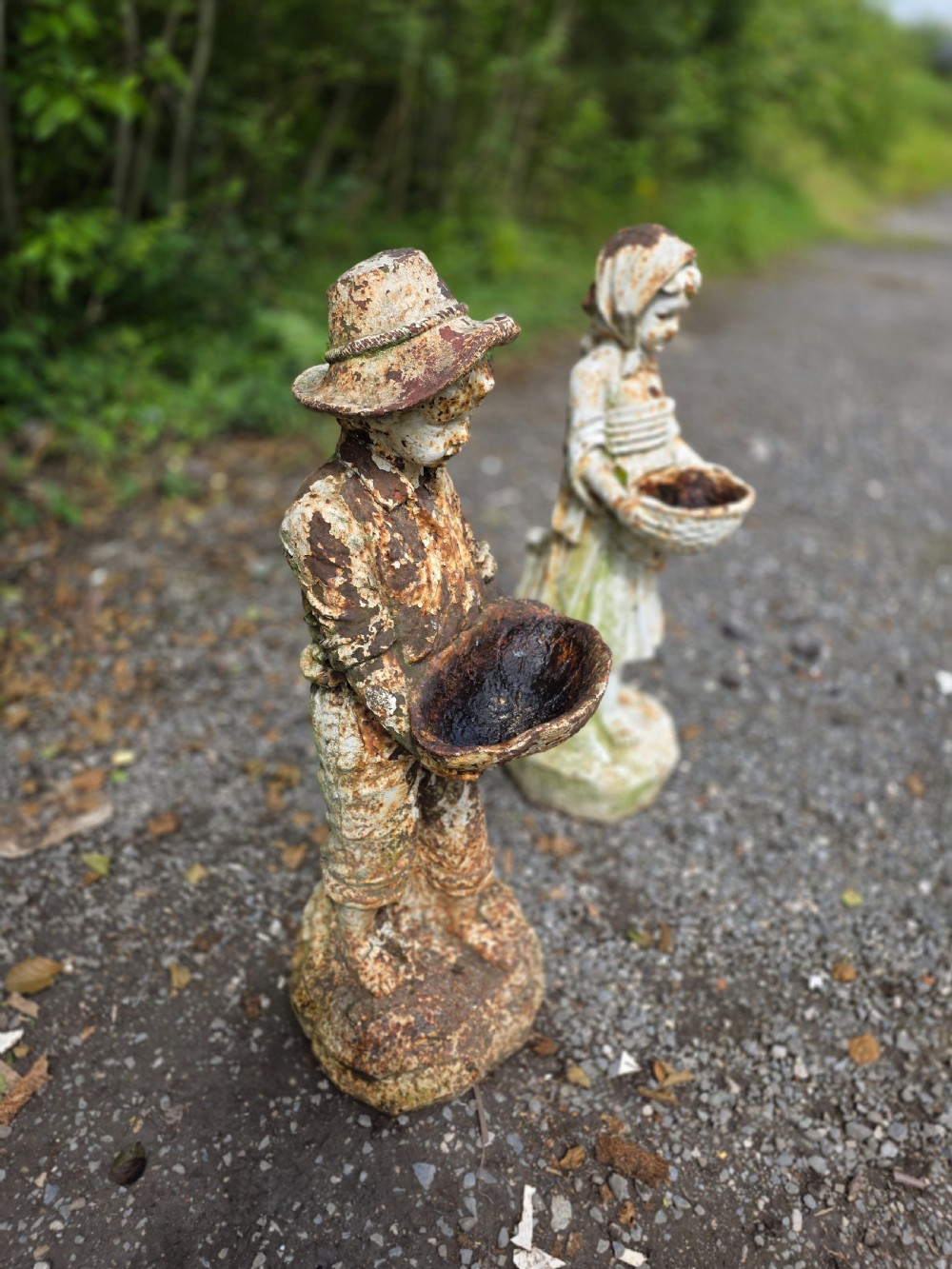 A pair of early 20th-century cast iron garden statues depicting a boy and girl in traditional attire holding small shallow basins. View VIII