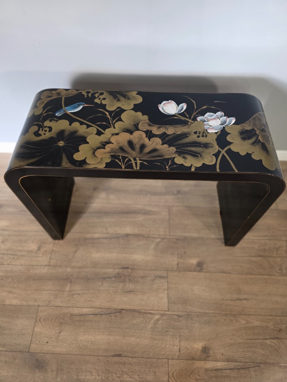 A mid-century black lacquered console table with rounded waterfall edges paired with a matching rectangular wall mirror decorated with hand-painted gold lotus leaves. View III