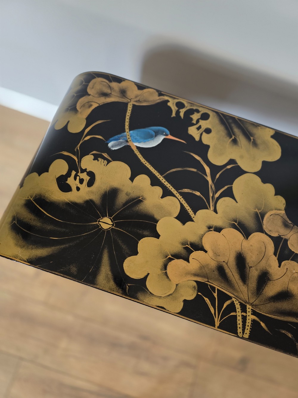 A mid-century black lacquered console table with rounded waterfall edges paired with a matching rectangular wall mirror decorated with hand-painted gold lotus leaves. View IV