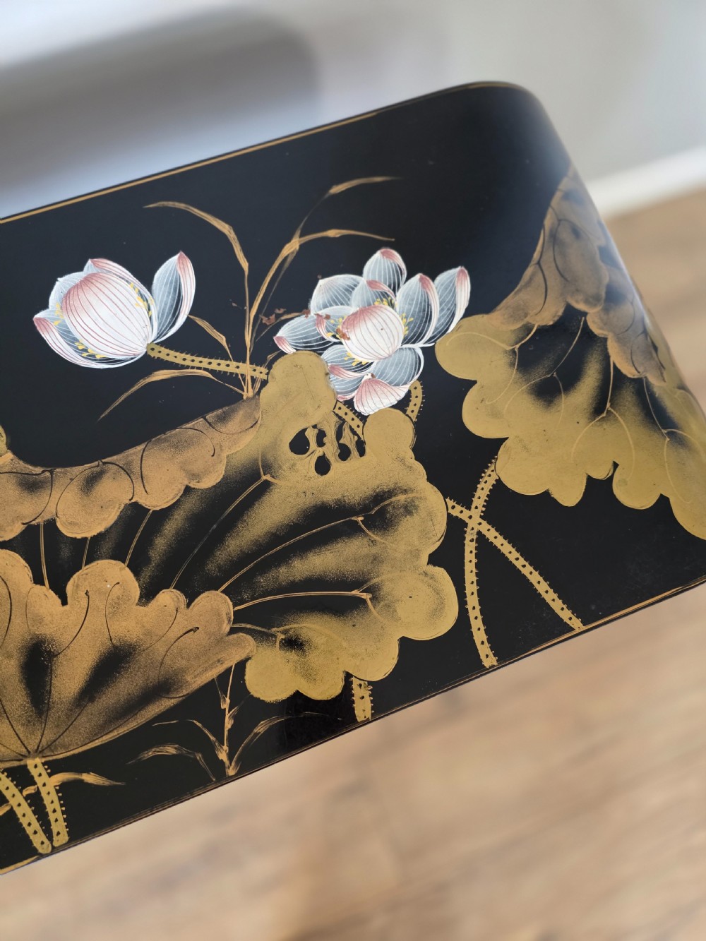 A mid-century black lacquered console table with rounded waterfall edges paired with a matching rectangular wall mirror decorated with hand-painted gold lotus leaves. View VI