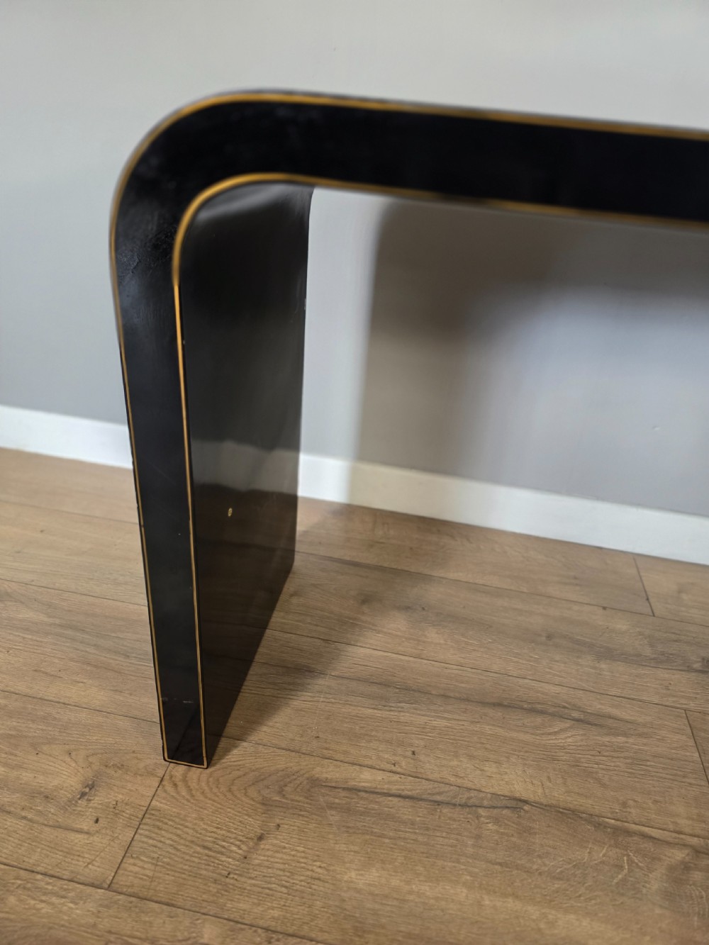 A mid-century black lacquered console table with rounded waterfall edges paired with a matching rectangular wall mirror decorated with hand-painted gold lotus leaves. View VII