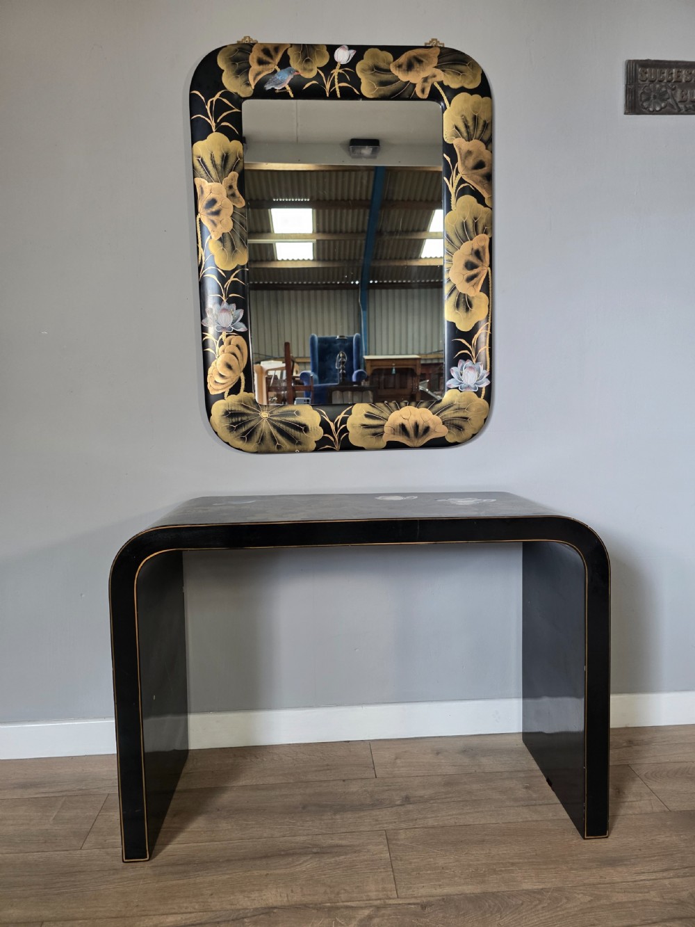 A mid-century black lacquered console table with rounded waterfall edges paired with a matching rectangular wall mirror decorated with hand-painted gold lotus leaves. View XIV