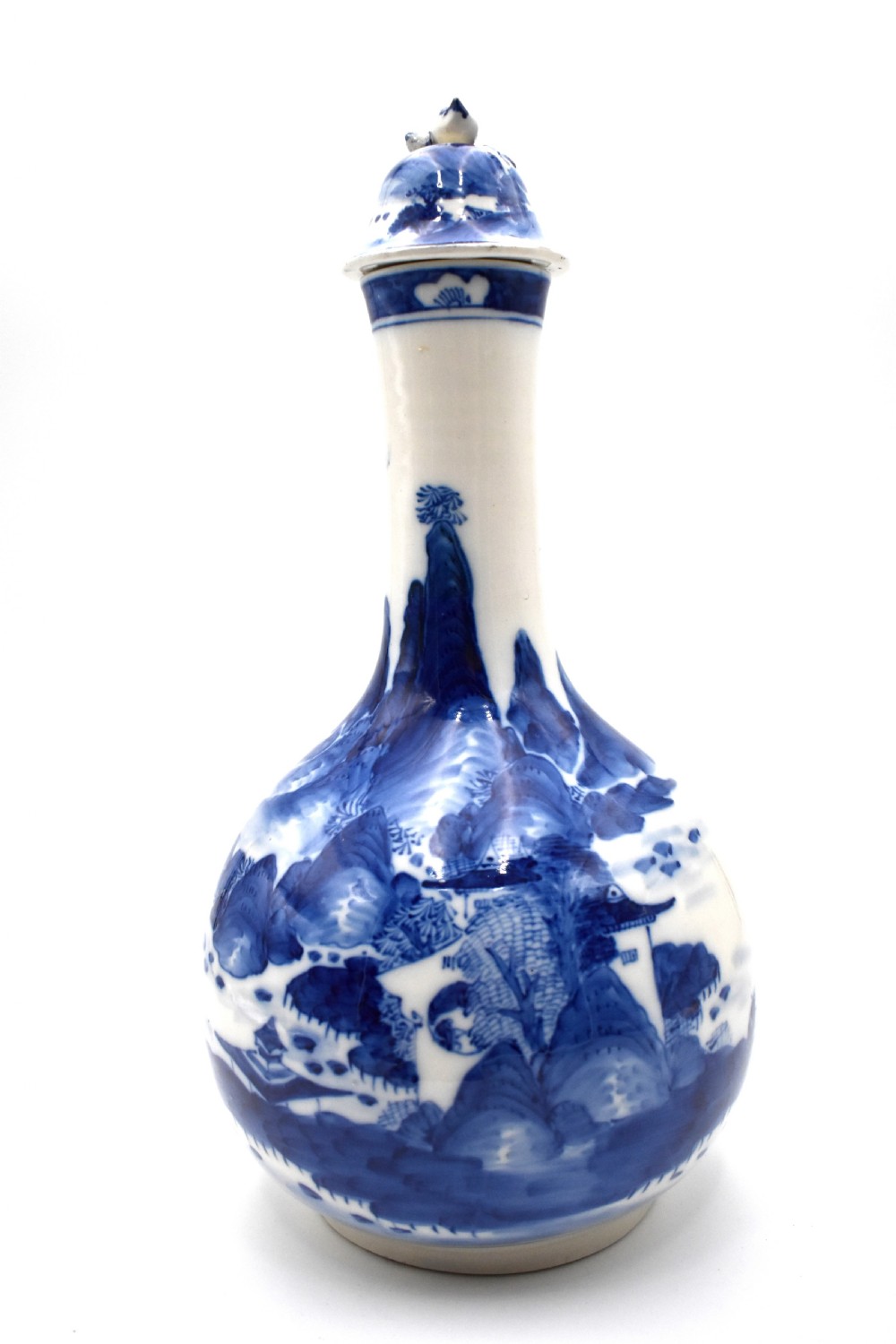 A 19th-century Chinese porcelain bottle vase with a matching lid, featuring hand-painted cobalt blue mountain landscape scenes on a white glazed body.