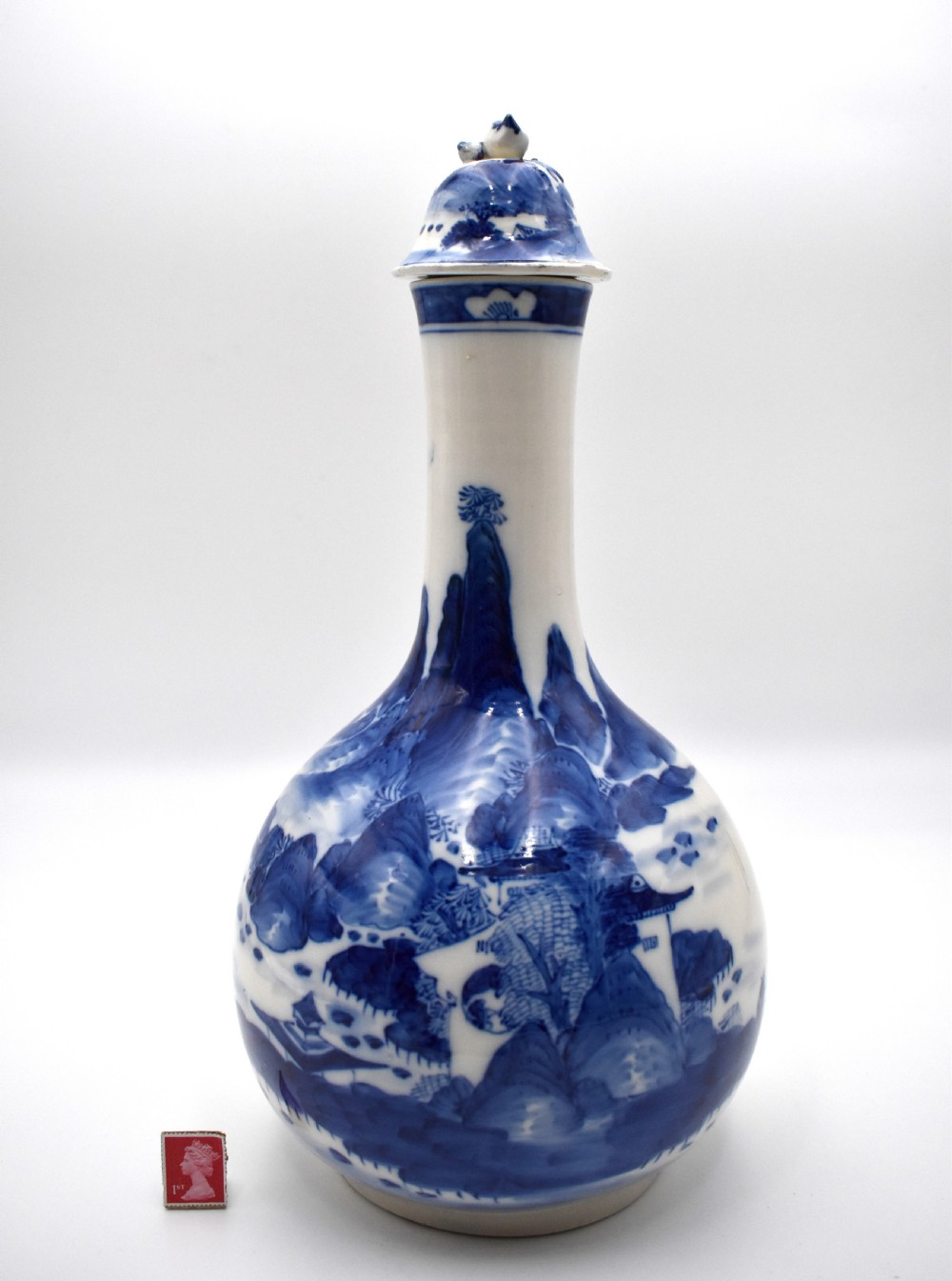 A 19th-century Chinese porcelain bottle vase with a matching lid, featuring hand-painted cobalt blue mountain landscape scenes on a white glazed body. View II
