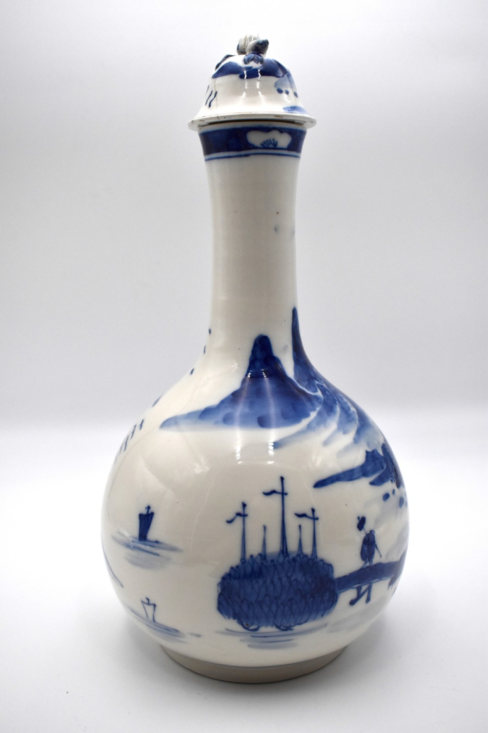 A 19th-century Chinese porcelain bottle vase with a matching lid, featuring hand-painted cobalt blue mountain landscape scenes on a white glazed body. View IV