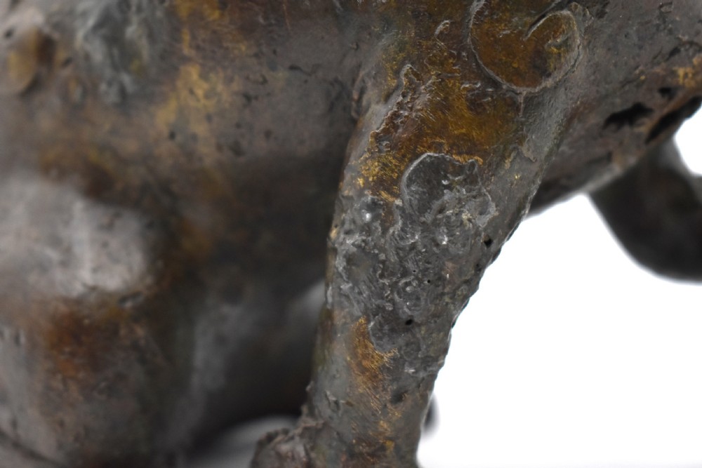 A 17th-century cast bronze Chinese guardian lion figure with an open mouth, pronounced ears, and a paw resting on a pierced sphere. View VI