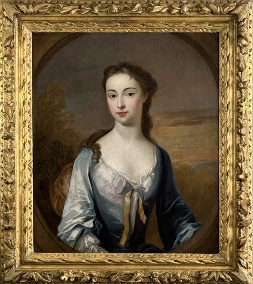 fig 2. An early eighteenth-century oil portrait painting depicting a woman in a blue dress set within an oval feigned surround and a carved giltwood frame.