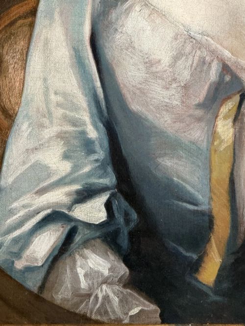 fig 6. An early eighteenth-century oil portrait painting depicting a woman in a blue dress set within an oval feigned surround and a carved giltwood frame.
