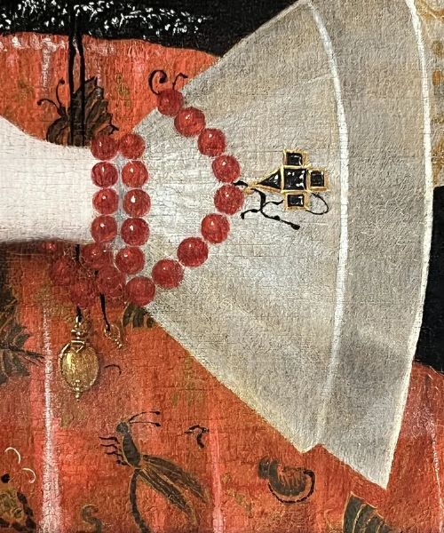 fig 3. A 17th-century oil painting depicting a noblewoman wearing a large white cartwheel ruff collar, embroidered floral bodice, black gown, and red coral bead bracelets.