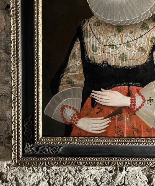 fig 4. A 17th-century oil painting depicting a noblewoman wearing a large white cartwheel ruff collar, embroidered floral bodice, black gown, and red coral bead bracelets.