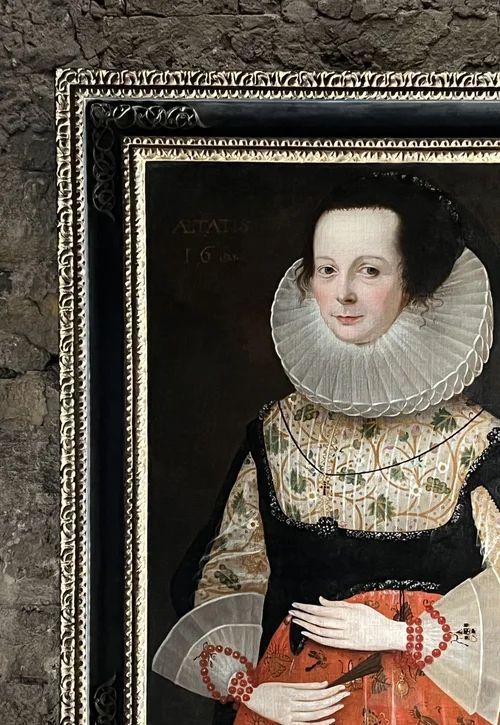 fig 5. A 17th-century oil painting depicting a noblewoman wearing a large white cartwheel ruff collar, embroidered floral bodice, black gown, and red coral bead bracelets.