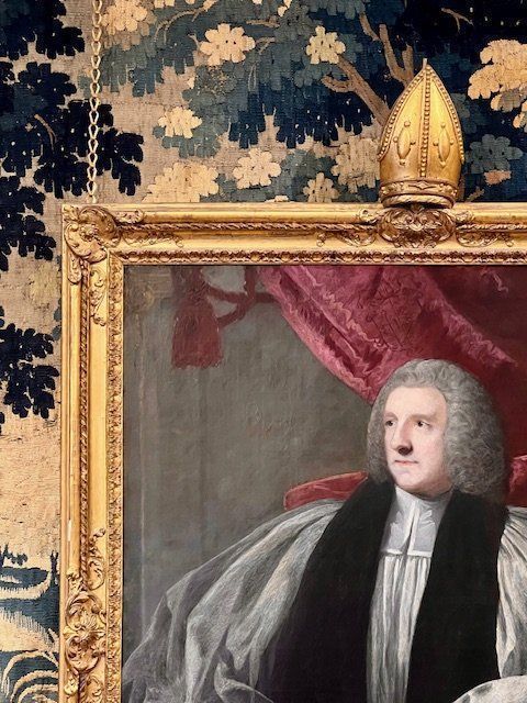 fig 6. An 18th-century oil portrait painting of an archbishop in clerical vestments housed in a carved giltwood frame topped with a mitre cresting.