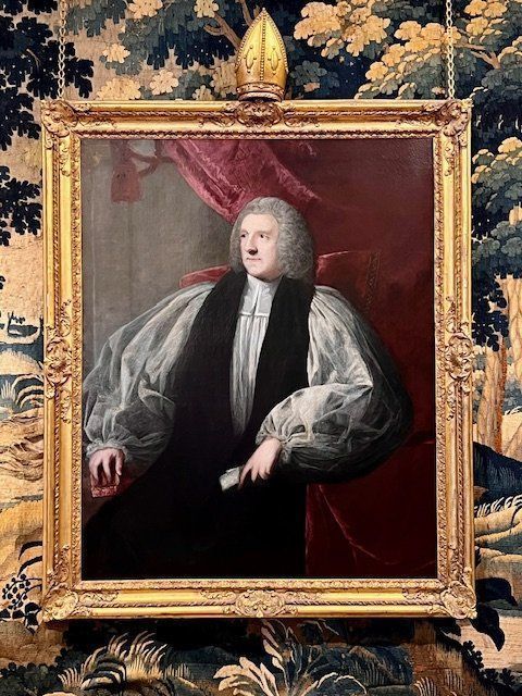 fig 7. An 18th-century oil portrait painting of an archbishop in clerical vestments housed in a carved giltwood frame topped with a mitre cresting.