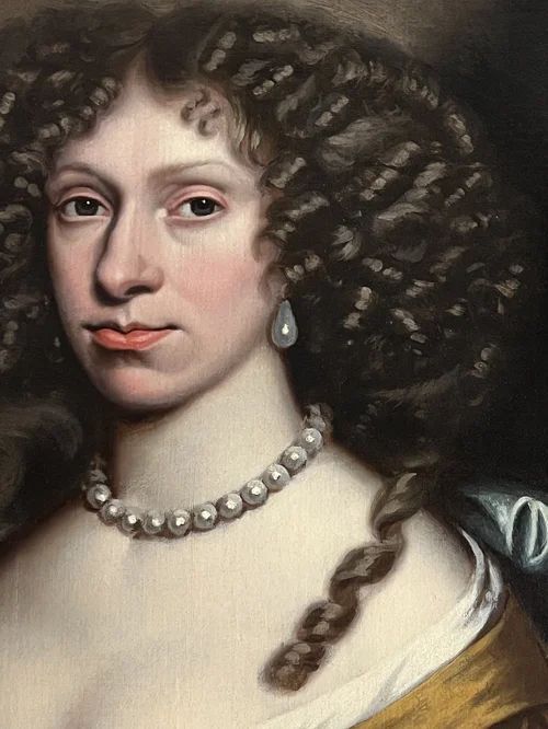 fig 4. A 17th-century oil portrait of a woman wearing a gold and blue gown with pearl jewellery, painted within a feigned oval canvas frame.