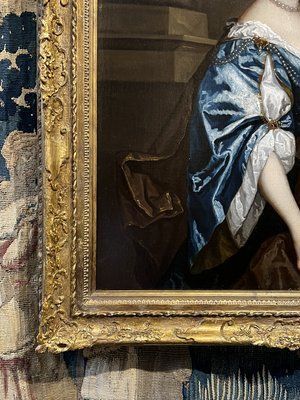 fig 3. A seventeenth-century portrait painting of a lady in a blue silk dress picking oranges, set within an ornate gilded frame.