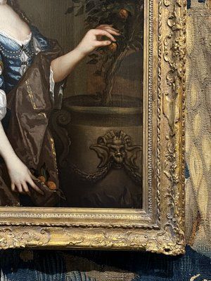 fig 6. A seventeenth-century portrait painting of a lady in a blue silk dress picking oranges, set within an ornate gilded frame.