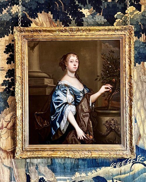 fig 10. A seventeenth-century portrait painting of a lady in a blue silk dress picking oranges, set within an ornate gilded frame.