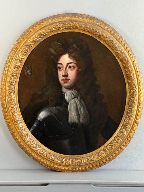 fig 7. An oval late 17th-century oil portrait of a long-haired nobleman in dark plate armour with a white cravat, set within a carved gilt frame.