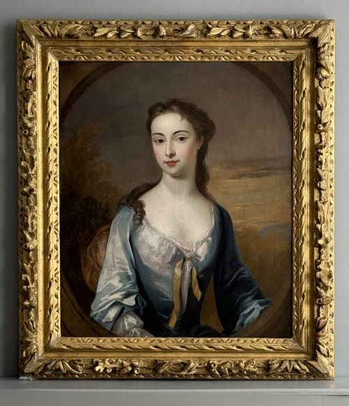 fig 1. An 18th-century oil portrait on canvas depicting a woman in a blue satin gown set within a feigned oval frame.