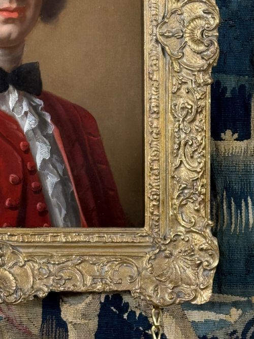 fig 2. An eighteenth-century oil portrait of a gentleman in a scarlet coat with a white cravat, set inside a carved giltwood frame.