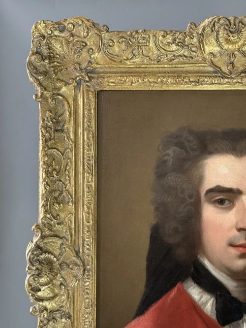 fig 3. An eighteenth-century oil portrait of a gentleman in a scarlet coat with a white cravat, set inside a carved giltwood frame.
