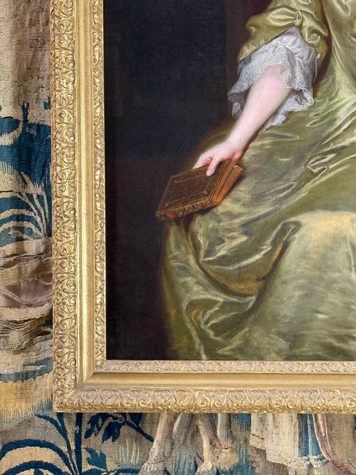 fig 1. An 18th-century oil portrait depicting a seated lady in a chartreuse silk dress with lace trim holding a book.