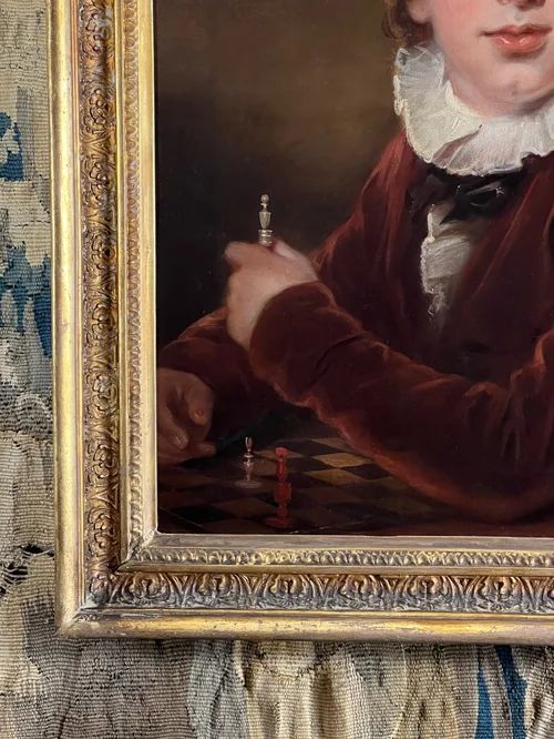 fig 2. A 19th-century portrait oil painting on canvas depicting a young boy in a brown jacket seated at a chessboard, enclosed in a gilded frame.