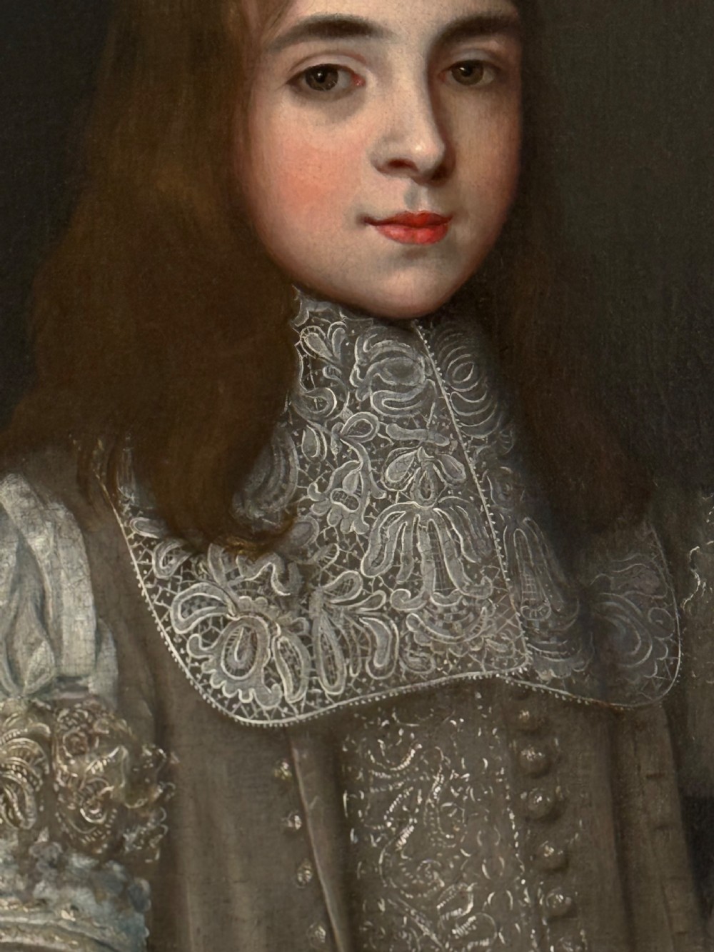 A seventeenth-century oil portrait depicting a young gentleman wearing an intricate lace collar and embroidered clothing in a carved silvered frame. View VI