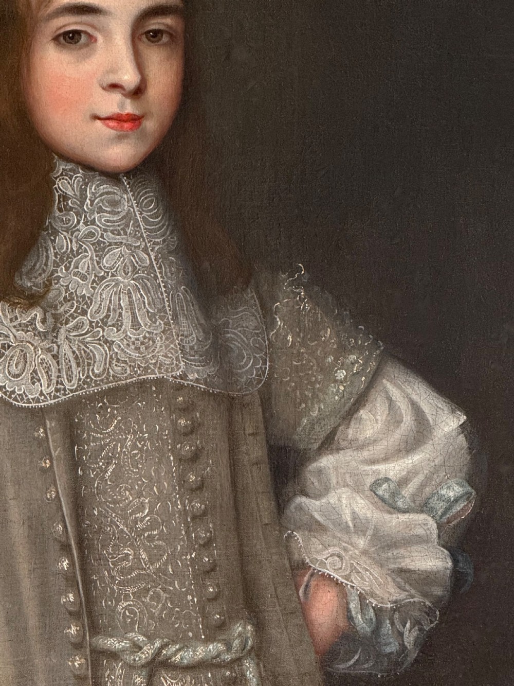 A seventeenth-century oil portrait depicting a young gentleman wearing an intricate lace collar and embroidered clothing in a carved silvered frame. View VII