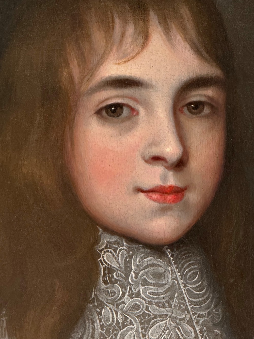 A seventeenth-century oil portrait depicting a young gentleman wearing an intricate lace collar and embroidered clothing in a carved silvered frame. View IX