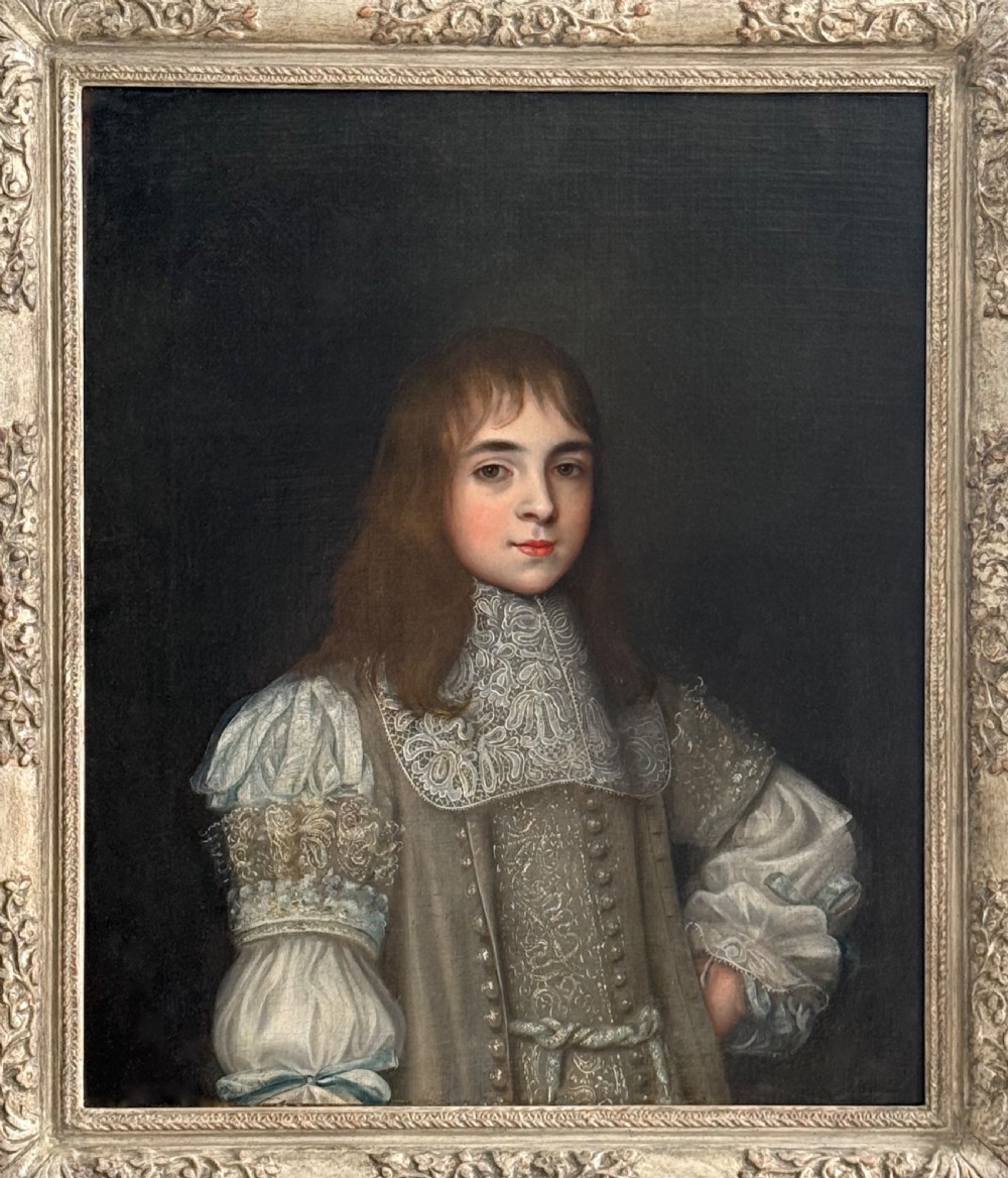 A seventeenth-century oil portrait depicting a young gentleman wearing an intricate lace collar and embroidered clothing in a carved silvered frame. View X