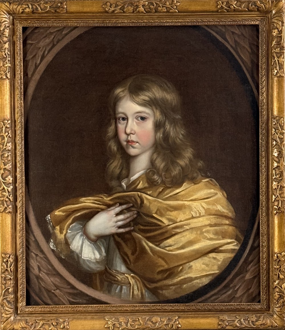 A 17th-century oil portrait of a young boy with long curled hair draped in golden-yellow silk, set within a painted trompe loeil oval border. View V