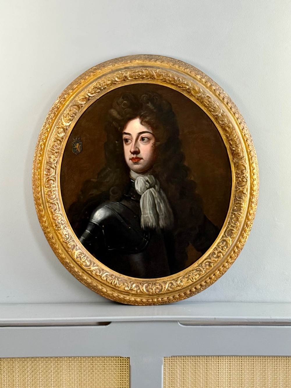 An oval late 17th-century oil portrait of a long-haired nobleman in dark plate armour with a white cravat, set within a carved gilt frame. View IX
