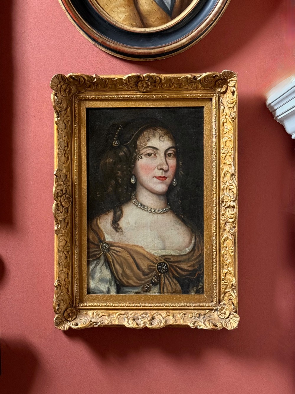 A seventeenth-century oil painting on canvas depicting a noblewoman with pearl jewellery, housed within an ornate carved gilt frame.