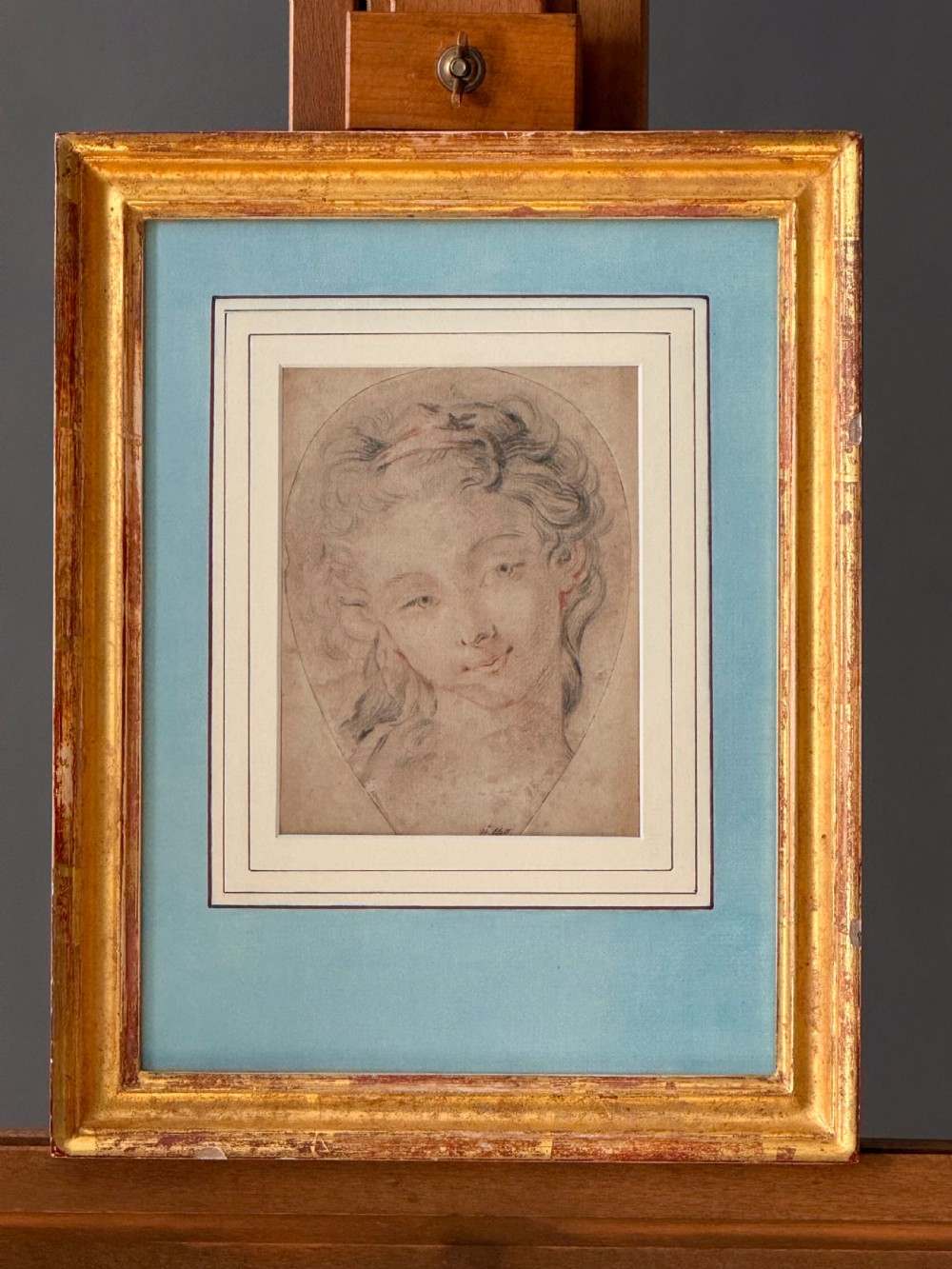 An 18th-century French Rococo chalk portrait drawing of a woman, displayed within a pale blue mount and an antique gilt frame. View IV