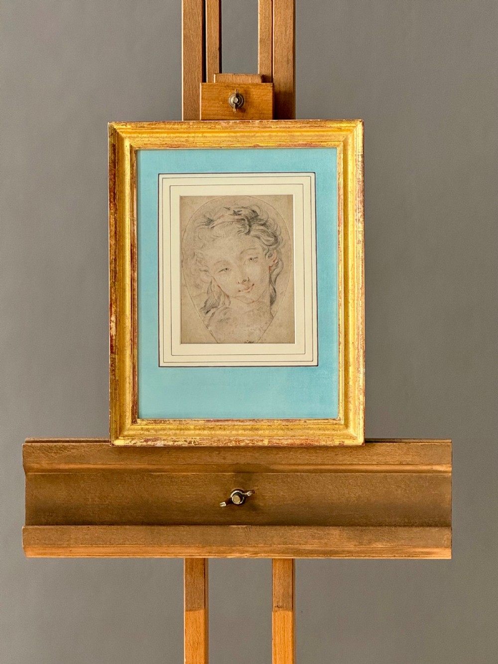 An 18th-century French Rococo chalk portrait drawing of a woman, displayed within a pale blue mount and an antique gilt frame. View VI