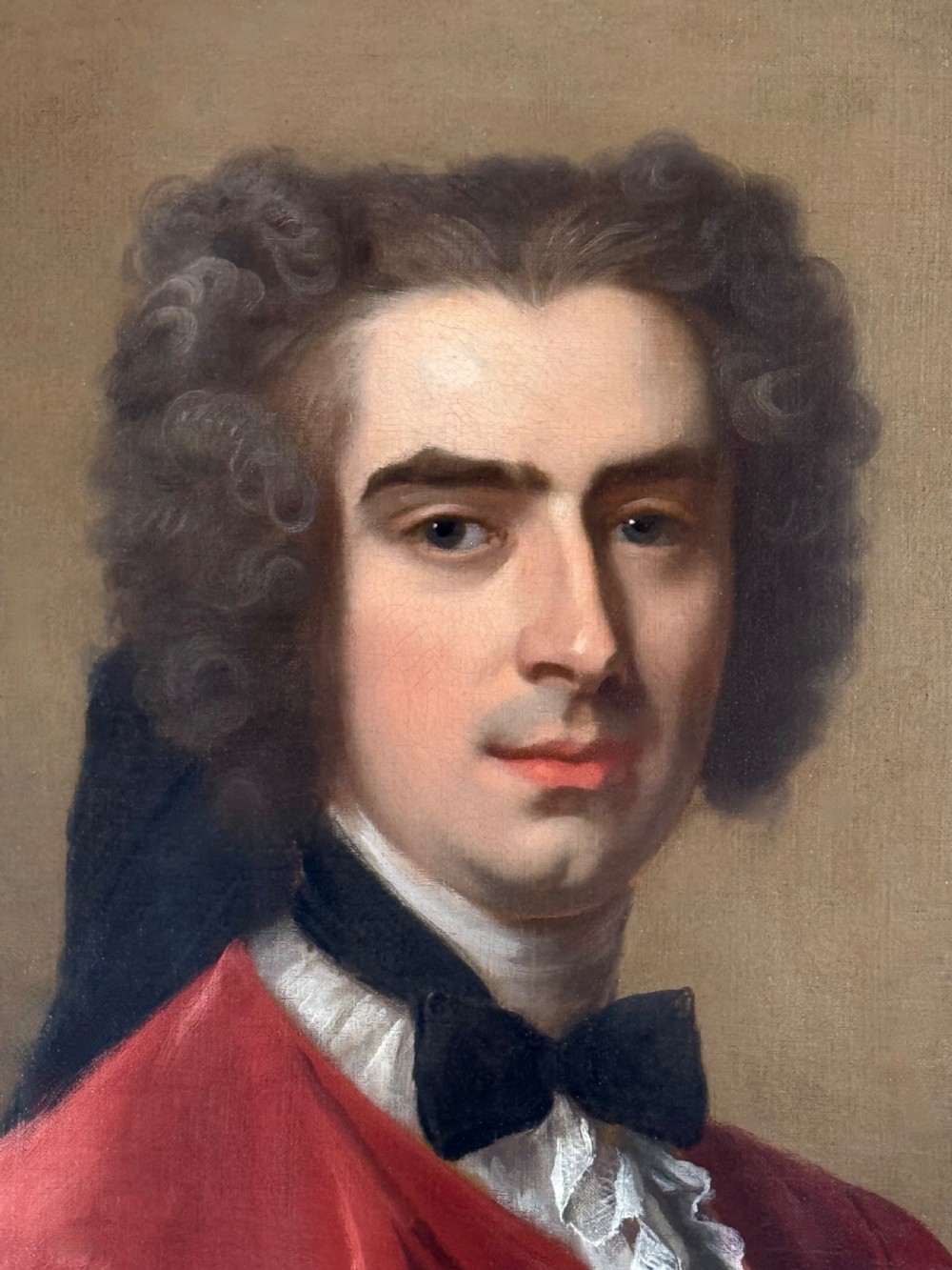 An 18th-century oil painting depicting a gentleman in a scarlet jacket with a white cravat, framed in an ornate gilded Rococo-style frame. View III