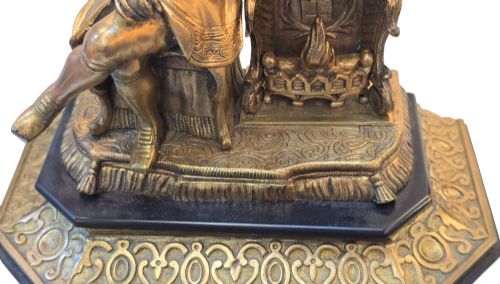 fig 2. A 19th-century French gilt bronze sculpture depicting a seated gentleman in historic dress holding a quill, supported by an ornate black base with metallic scroll feet.