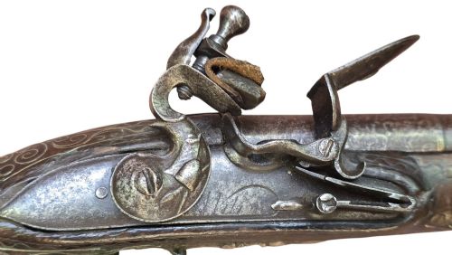 fig 1. An early 19th-century Ottoman Balkan flintlock holster pistol featuring a dark wood stock inlaid with silver wire scrollwork and a cast brass pommel.