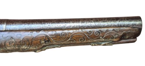 fig 3. An early 19th-century Ottoman Balkan flintlock holster pistol featuring a dark wood stock inlaid with silver wire scrollwork and a cast brass pommel.