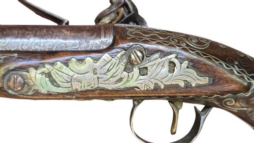 fig 5. An early 19th-century Ottoman Balkan flintlock holster pistol featuring a dark wood stock inlaid with silver wire scrollwork and a cast brass pommel.