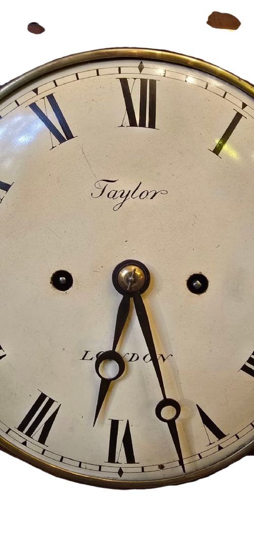 A Georgian mahogany bracket clock featuring brass star and floral motifs, a pineapple finial, brass ball feet, and a white dial marked Taylor London with Roman numerals. View VIII