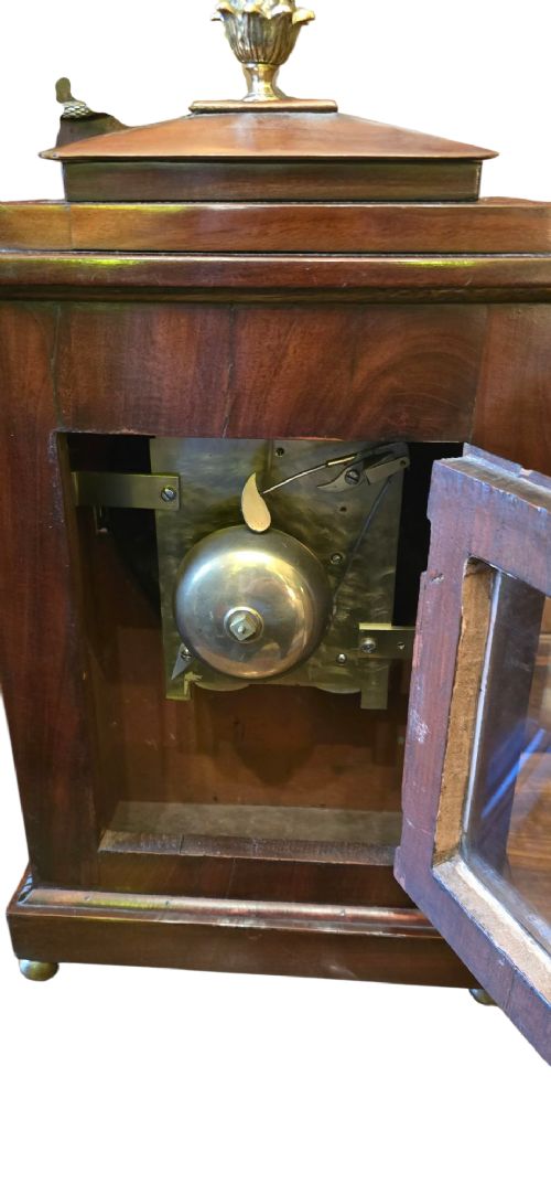 A Georgian mahogany bracket clock featuring brass star and floral motifs, a pineapple finial, brass ball feet, and a white dial marked Taylor London with Roman numerals. View XI