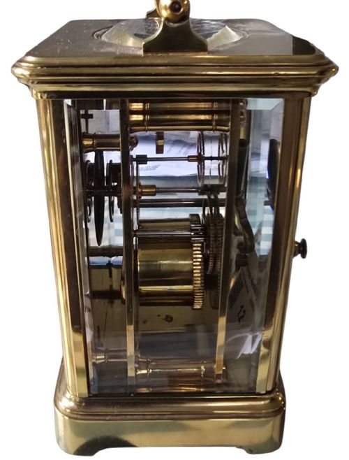 A rectangular French gilt-brass carriage clock featuring bevelled glass panels, a white enamel dial with Roman numerals, and a hinged top handle. View VI